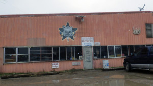 A photo of a wrecking yard with the Self Help Radio logo in the place of the regular sign